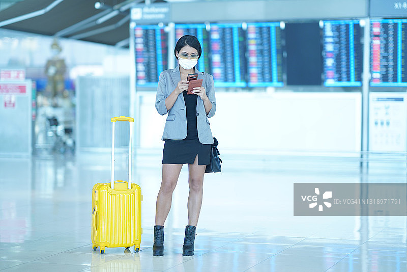 女乘客站在登机牌前用手机查看航班时刻表图片素材