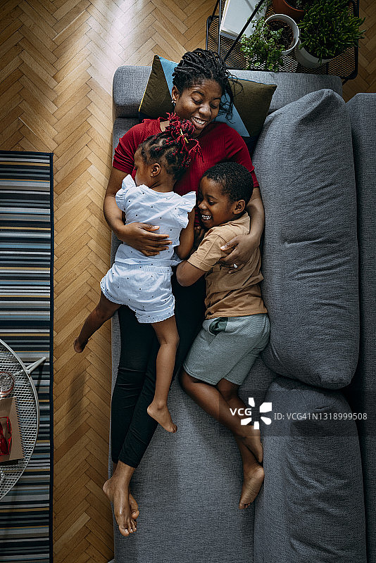 俯视图快乐大笑的母亲拥抱她的女儿和儿子在沙发上图片素材