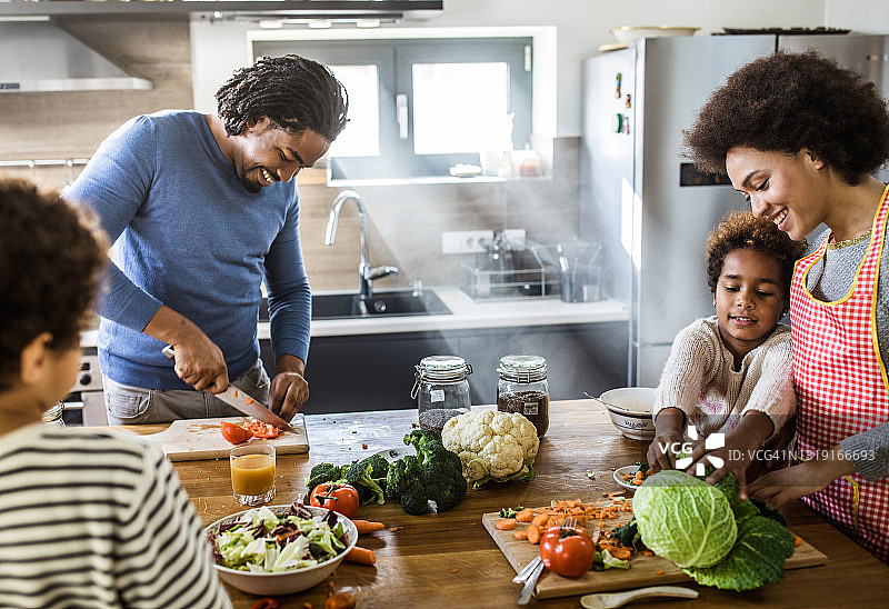 快乐的非裔美国家庭在厨房准备食物。图片素材