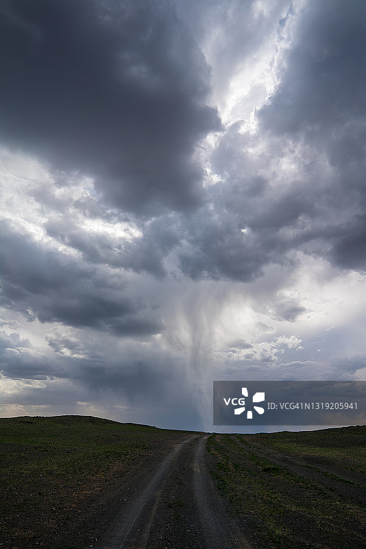 龙卷风在暴风雨的天空中掠过蒙古一条土路，垂直放置图片素材