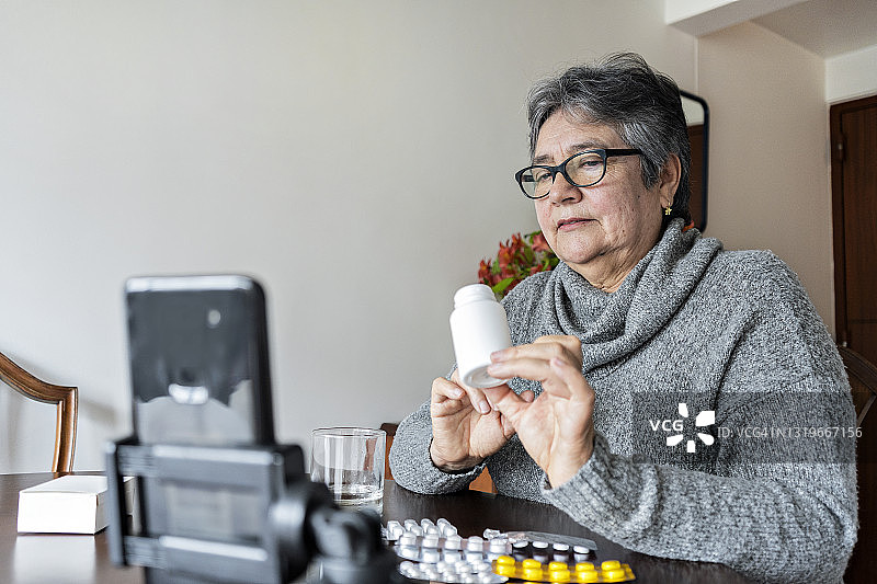 在家中接受远程咨询的老年拉丁妇女接受药物使用说明图片素材