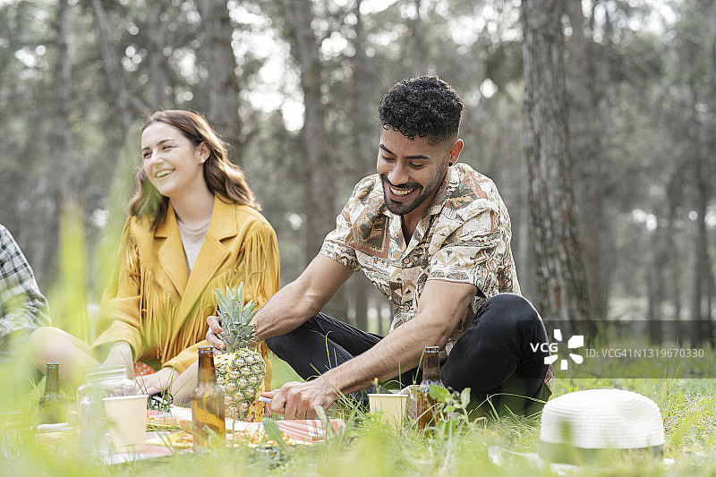 男性和女性朋友享受在森林野餐图片素材