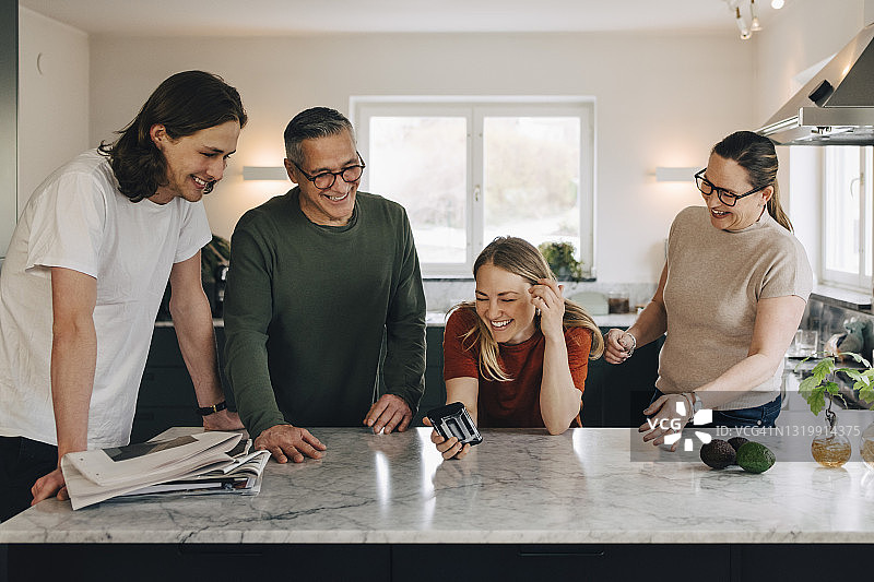 在厨房里与家人分享智能手机的快乐女人图片素材
