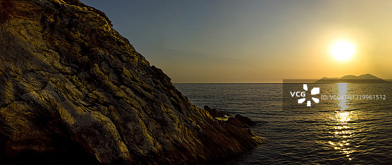 日落在岩石海岸和平静的海洋图片素材