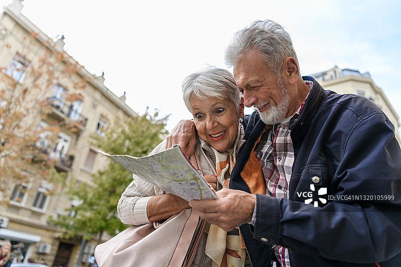 老人和他的妻子带着旅游地图在市区散步。图片素材