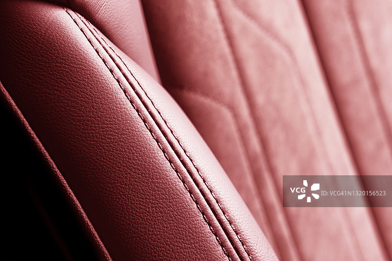 现代豪华汽车红色皮革与阿尔坎塔拉内饰。部分红色皮革汽车座椅细节与白色缝线。高档车的内饰。穿孔皮革座椅隔离。穿孔皮革。图片素材