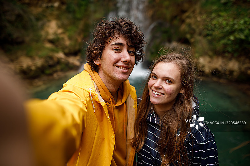 一对年轻夫妇在山间瀑布前自拍图片素材