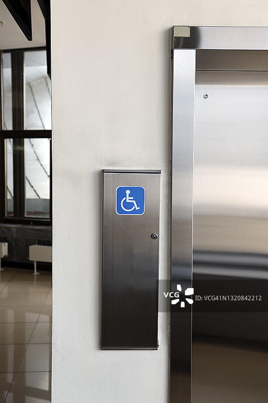 残疾人标识，现代钢电梯客舱在一个商业大堂或酒店，商店，室内，办公室，视角广角。图片素材