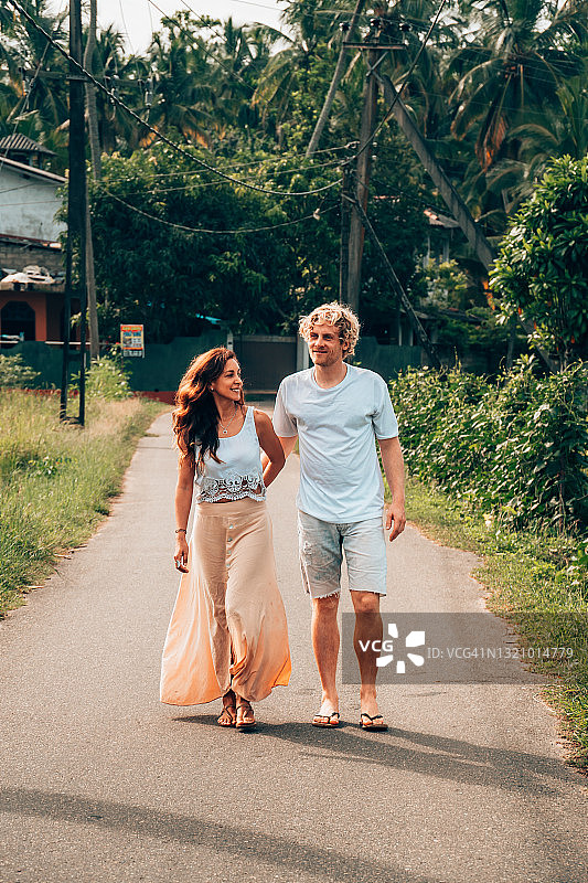 一对深情的成年夫妇手牵手走在斯里兰卡的热带公路上。图片素材