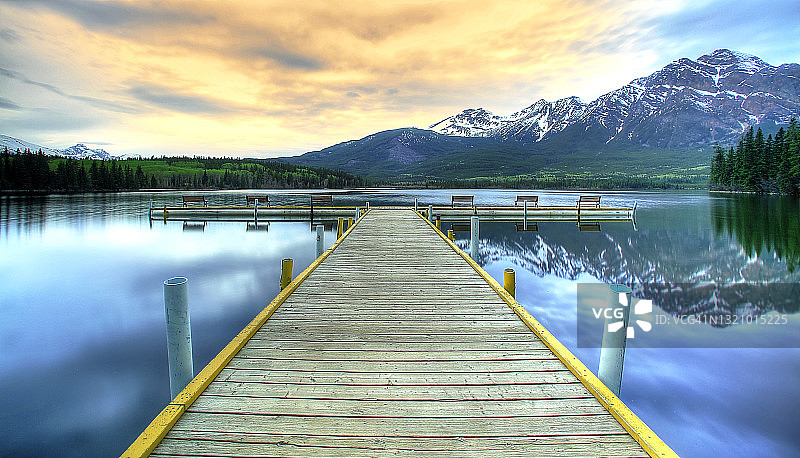 白雪皑皑的山脉和倒影湖上的木桥图片素材