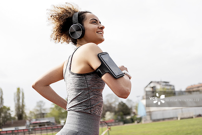 年轻女子戴着耳机在跑道上跑步图片素材