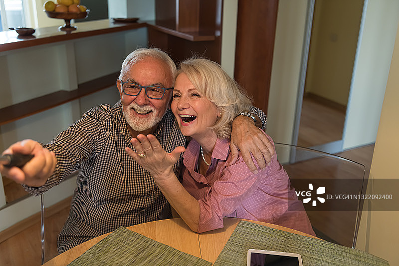 一对老年夫妇在家里享受时光，同时拍摄快乐和可爱的时刻。图片素材