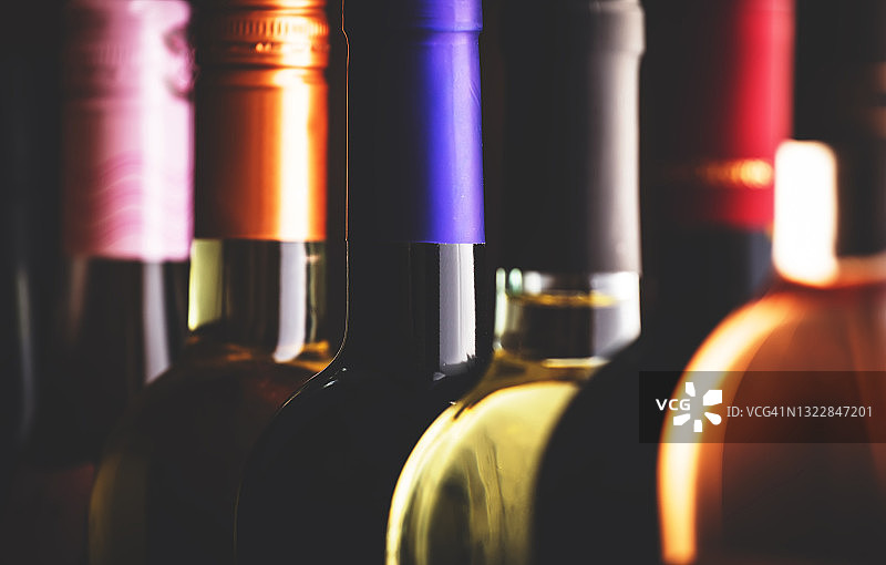 葡萄酒收藏排在酒窖，酒厂地下室，酒吧或商店的深色木制背景图片素材