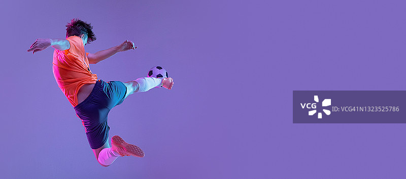 年轻的白人男子，男性足球运动员训练孤立在梯度蓝粉色背景霓虹灯图片素材