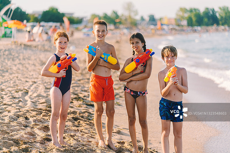 孩子们拿着水枪在海滩度假的肖像图片素材