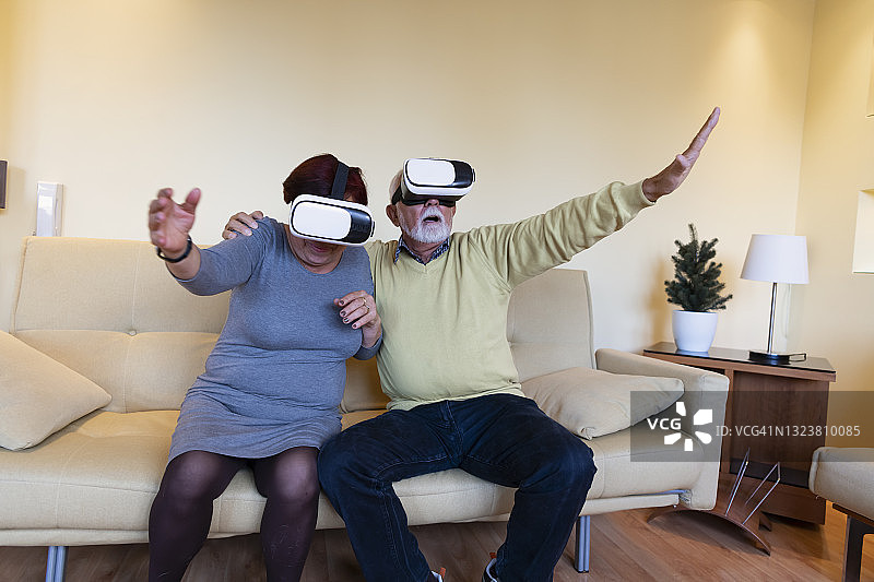 兴奋的老男人和他的妻子玩VR眼镜。虚拟现实已经成为现实。图片素材