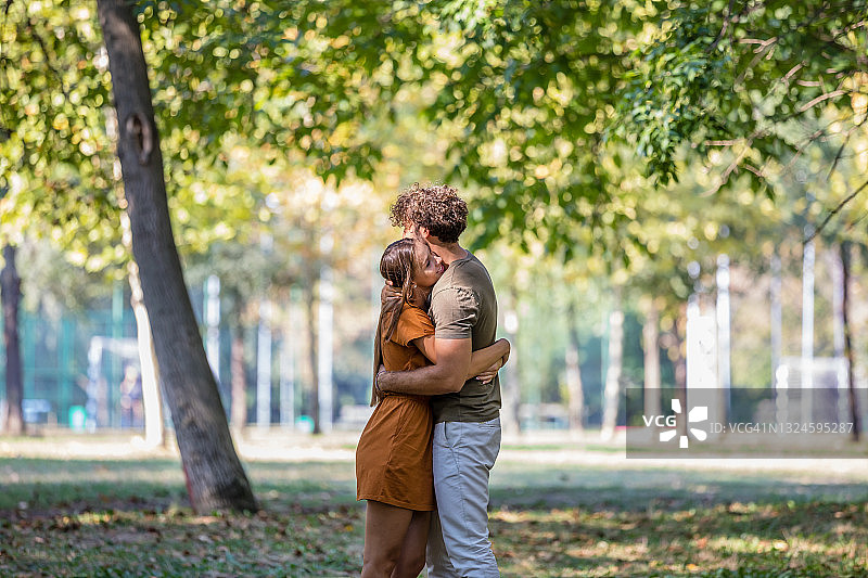 一个年轻人和他的妻子在城市公园里轻松地散步，享受一天。图片素材
