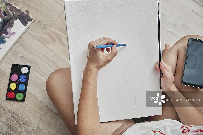 一个女孩正在用她的智能手机学习画画图片素材