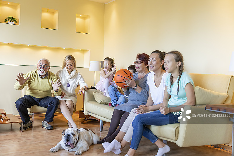 一个欢呼的家庭正在一起看电视上的篮球比赛。图片素材