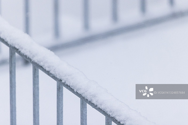 白雪覆盖的栏杆的特写。图片素材