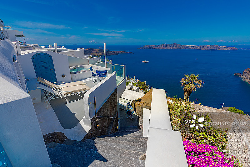 夏日全景度假，奢华著名的欧洲目的地。希腊圣托里尼岛的白色建筑。完美的旅游风景，粉红色的花朵和游轮在阳光和蓝天。惊人的观点图片素材