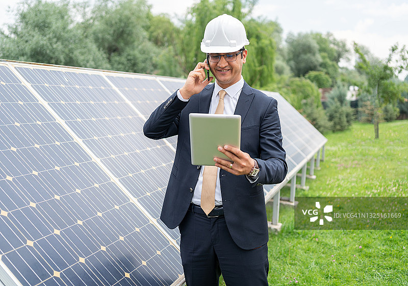 一男经理工程师İn安全帽检查平板太阳能电站太阳能电池板系统的操作图片素材