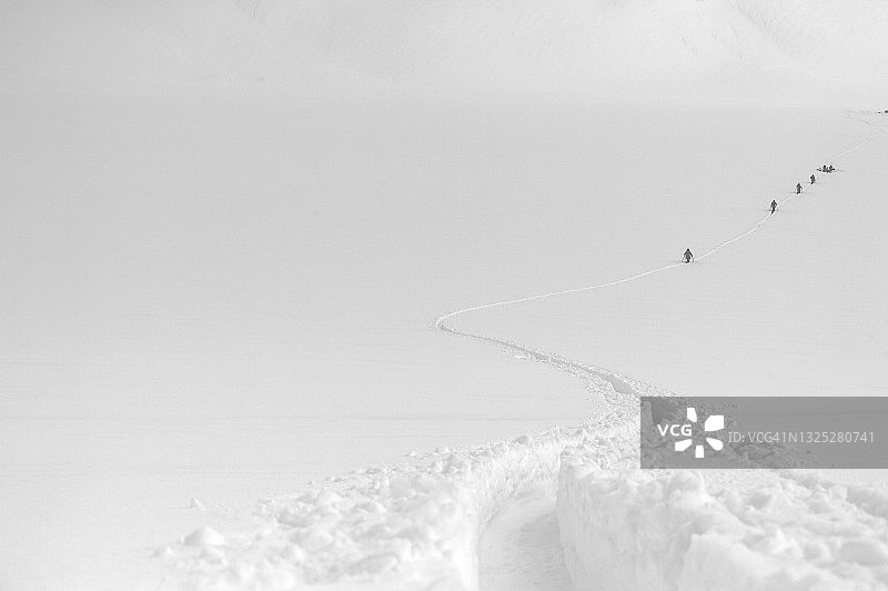 野外滑雪者在暴风雪中爬上雪坡图片素材