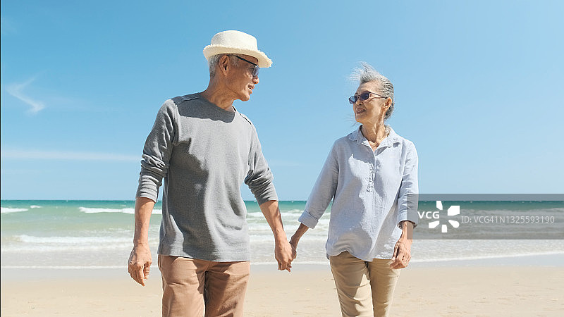 退休夫妇在海滩上快乐地慢跑。图片素材