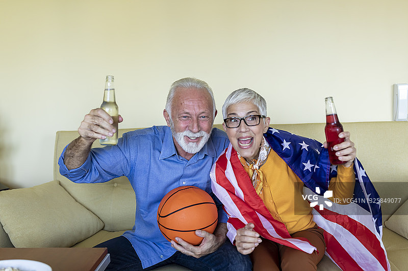 一对老夫妇正在享受美国国家篮球队的比赛在家里。图片素材