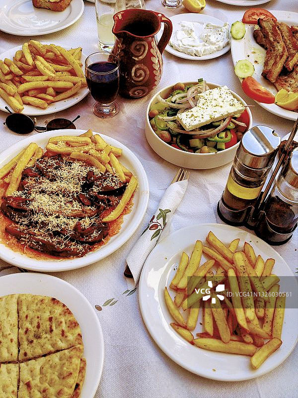 希腊菜。桌面俯瞰Imam bayildi(塞满茄子/茄子)，薯条，羊排，皮塔面包，沙拉，酸奶黄瓜和红酒图片素材