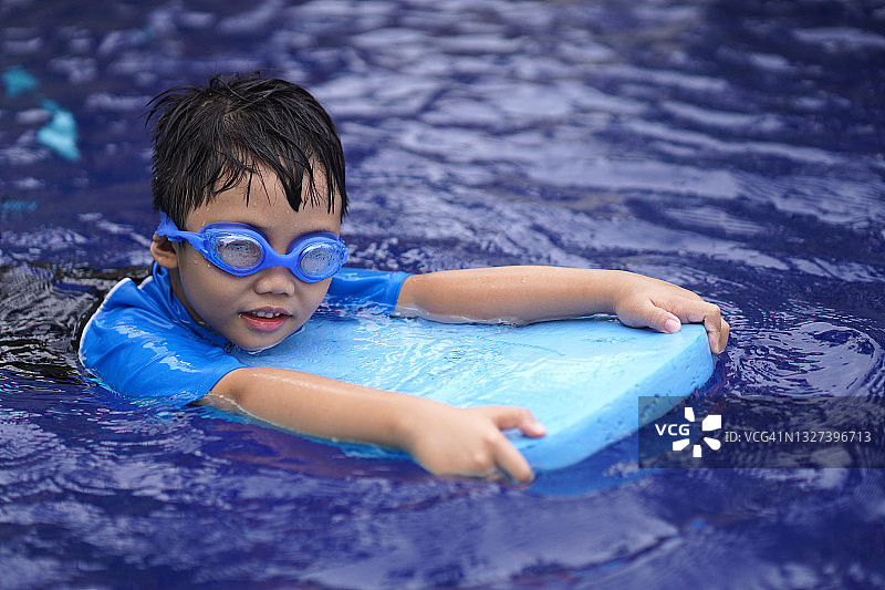 小男孩在游泳池里。图片素材