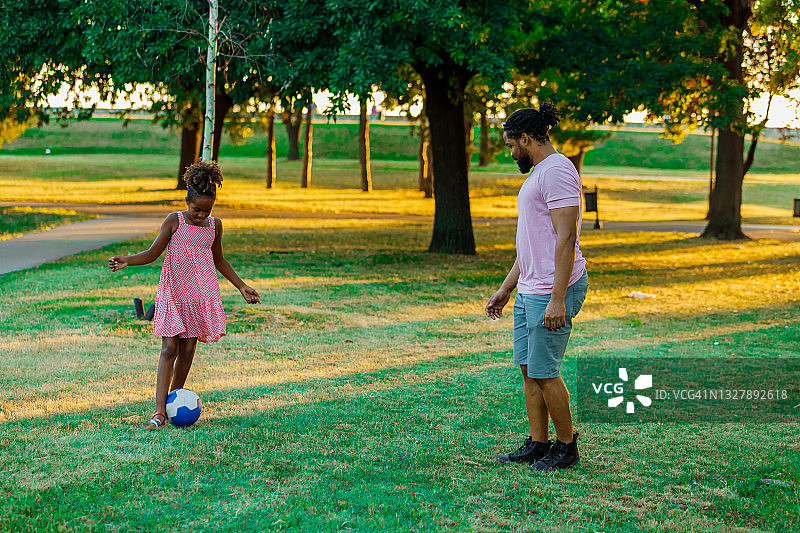 快乐的非洲裔美国家庭正在大自然的户外踢足球。图片素材
