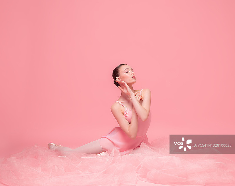 美丽的女孩，优雅的芭蕾舞者在粉红色的工作室背景孤立摆姿势。艺术，运动，动作，灵活性，灵感概念。图片素材