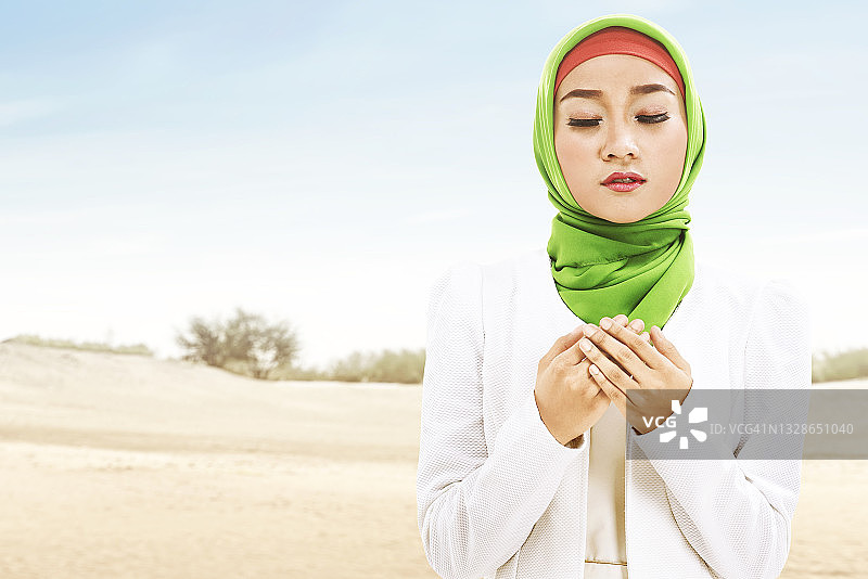 亚洲穆斯林妇女戴着面纱祈祷，手上戴着念珠图片素材
