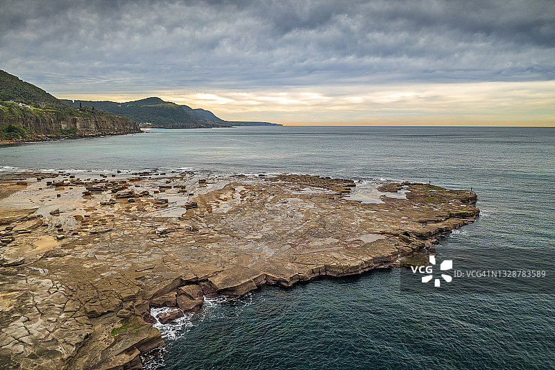 海岸岬角、海浪、大海和山脉平坦的岩石图片素材