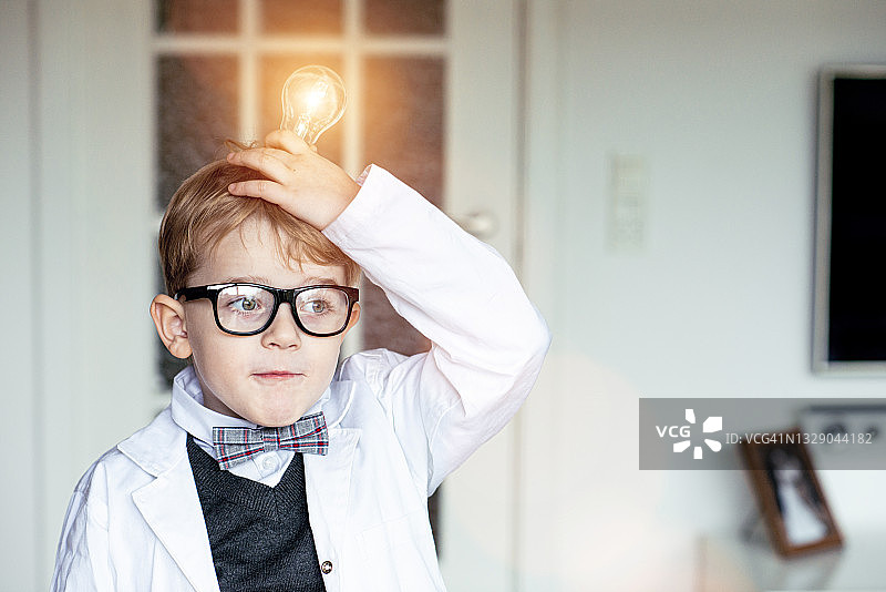 儿童发明家在拿着灯泡的时候想到了一个好主意图片素材