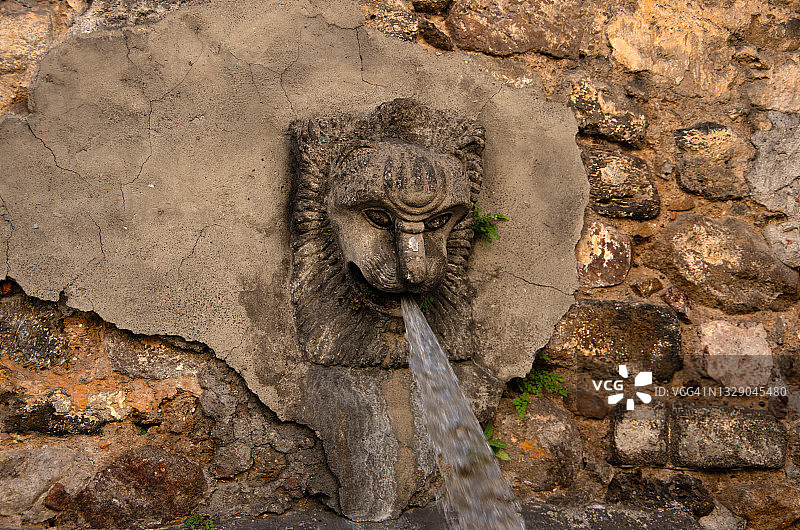古色古香的石雕狮头喷泉在石壁上图片素材