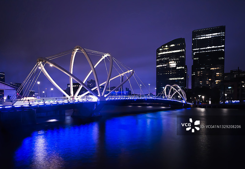 灯火通明的桥在夜晚的现代城市河上图片素材