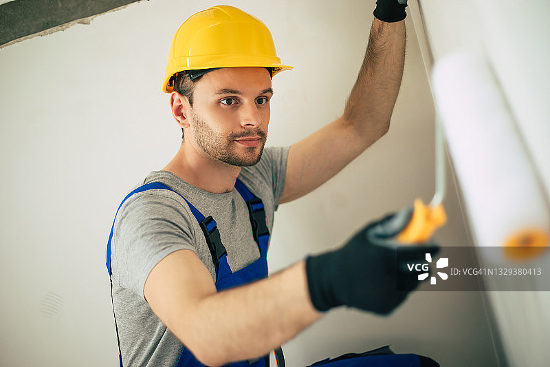 年轻的家庭修理男或工人忙于房屋装修，持有建筑设备，穿着休闲的工作服在新建图片素材