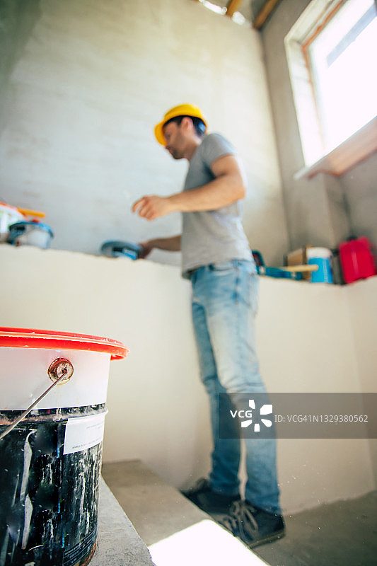 年轻的家庭修理男或工人忙于房屋装修，持有建筑设备，穿着休闲的工作服在新建图片素材