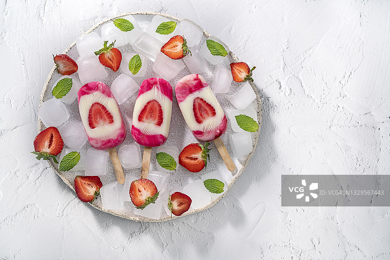 草莓自制冰棒配薄荷叶冰块，白色背景，白色盘子图片素材