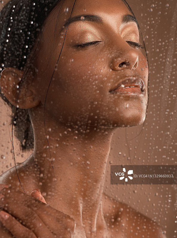 一个美丽的年轻女人的肖像有一个清爽的淋浴在一个棕色的背景图片素材