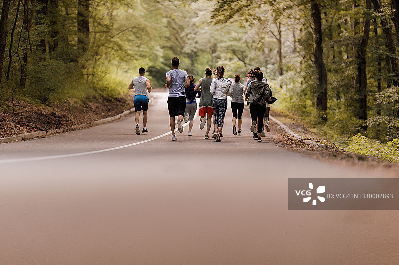 后方的运动员跑马拉松沥青公路在自然。图片素材