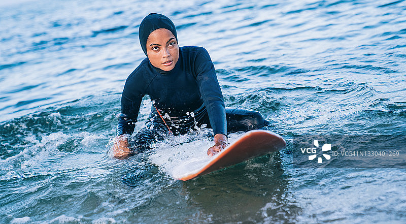 戴着头巾的女性冲浪者在海里图片素材