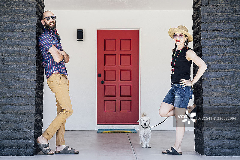 中间的成年夫妇和狗狗站在房子前面图片素材