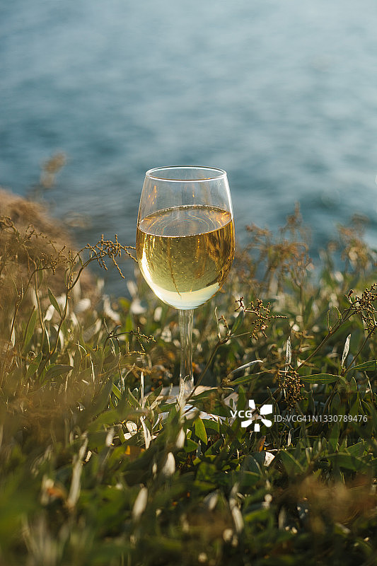 夏季海上野餐。一杯白葡萄酒，模糊了蓝色海水的背景。图片素材