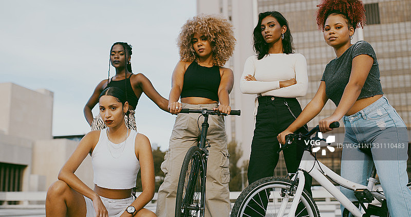 白天，一群不同的女性在城市里骑着自行车摆姿势图片素材