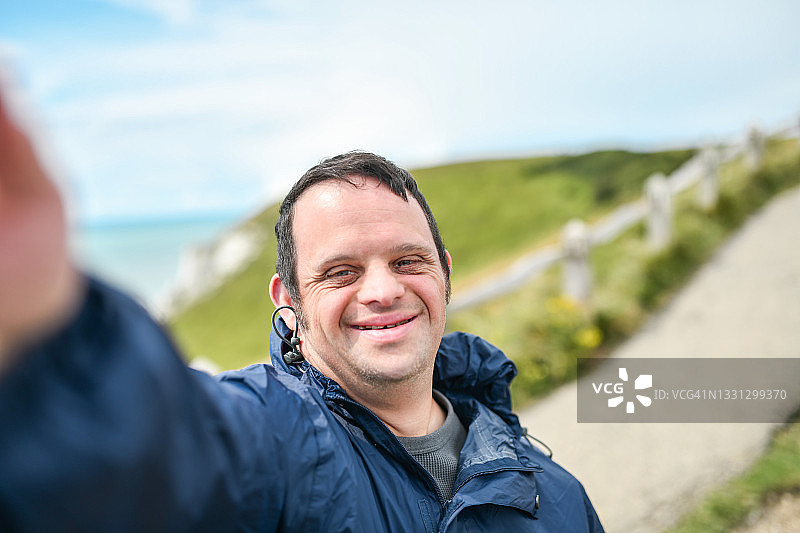 一名患有唐氏综合症的微笑男子在英国海边自拍图片素材