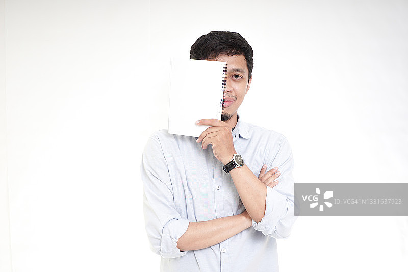 亚洲年轻人用书遮住脸图片素材