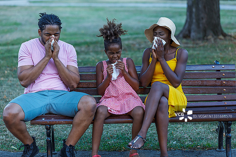 过敏的非洲家庭正在公园里擤鼻子。图片素材
